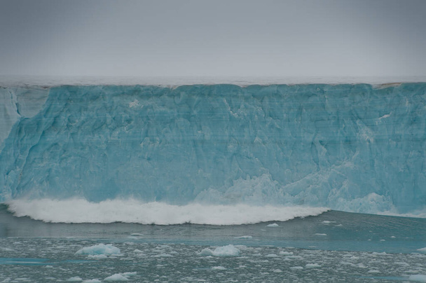 A huge piece of glacial ice wall has collapsed into sea causing a wave of ocean heading towards camera.Global warming .Climate Change. - Photo, image