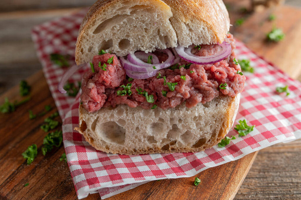 Tatar sandwich with red onions and parsley on a french baguette. Closeup and front view - Zdjęcie, obraz