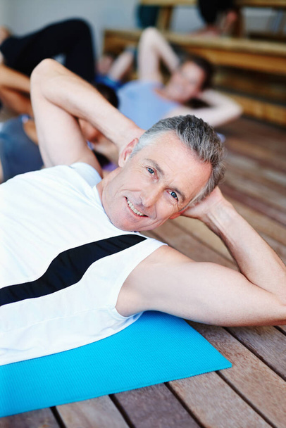 He loves his exercise. A group of people in a gym class doing stomach crunches - Foto, Imagen