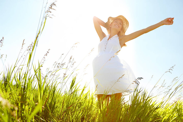 Get away from it all...A carefree young woman standing with her arms outstretched in a meadow while smiling blissfully - Photo, Image