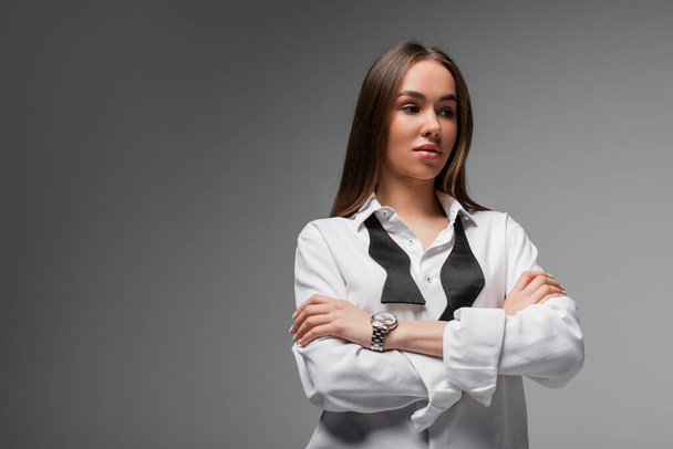 portrait of confident woman in white shirt and black tie standing with crossed arms isolated on grey, gender equality concept  - Photo, Image