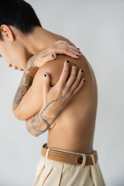 částečný pohled na ženu bez trička zakrývající prsa při objímání se izolovaně na šedé - Fotografie, Obrázek