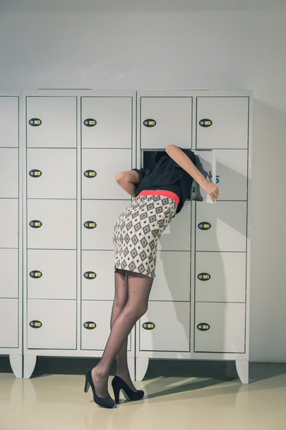 Beautiful young woman putting her head in a locker - Fotoğraf, Görsel