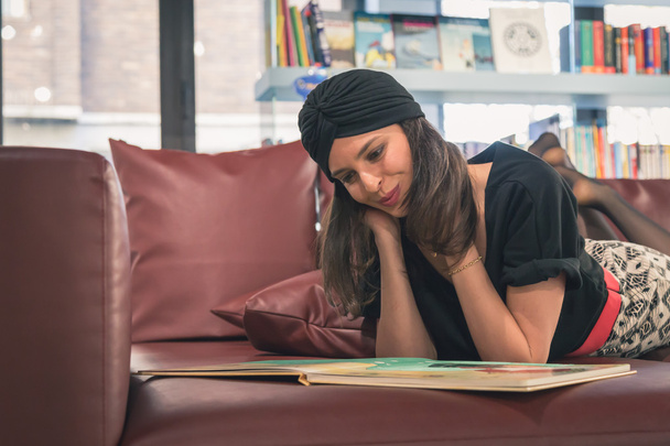 Beautiful young brunette reading book in a bookstore - Foto, Bild