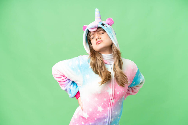 Chica joven con pijama de unicornio sobre fondo de croma clave aislado que sufre de dolor de espalda por haber hecho un esfuerzo - Foto, Imagen