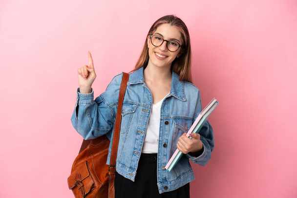Junge kaukasische Studentin isoliert auf rosa Hintergrund zeigt und hebt einen Finger im Zeichen der besten - Foto, Bild
