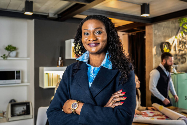 Empresaria africana trabajando dentro de una oficina moderna con el equipo multiétnico detrás de ella - Concepto de liderazgo y trabajo en equipo logrando objetivos - Enfoque en los ojos - Foto, imagen