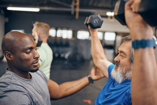 Fitness, old man and personal trainer coaching with dumbbell weightlifting, muscle support and gym in retirement. Health, exercise and workout at senior training club, sports coach helping grandpa - Foto, Imagem