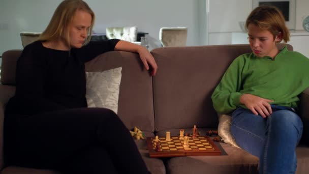 MS - Junge spielt Schach mit seiner Mutter zu Hause auf dem Sofa sitzend 5 - Filmmaterial, Video