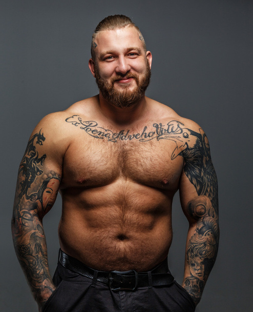Brutaali valtava mies tatuoinnit ja parta hymyilevä
 - Valokuva, kuva