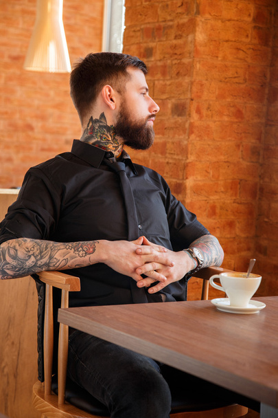 Poważny mężczyzna w kawiarni z kubkiem kawy - Zdjęcie, obraz