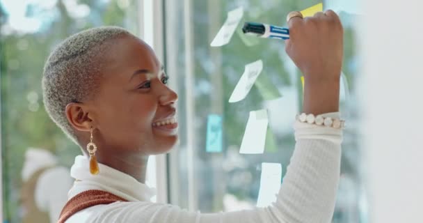 Мыслительная, бравурная и чернокожая женщина с улыбкой на доске пишет заметки на стеклянной стене для креативной идеи. Стратегия, планирование на липкой ноте на семинаре и будущие цели бизнес-проектов - Кадры, видео