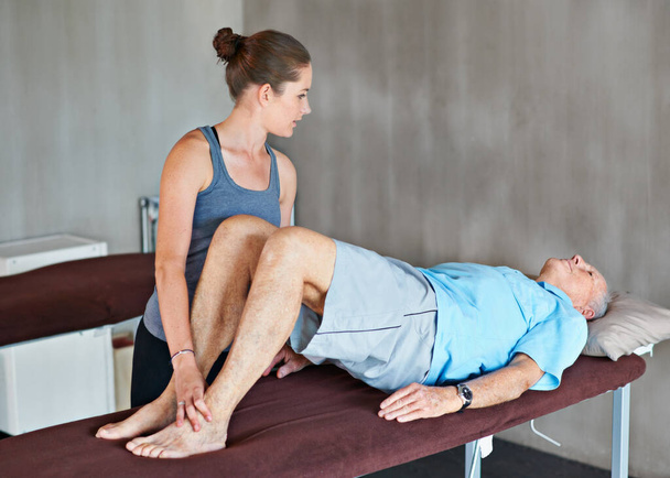 Helping her patients stay strong and healthy. a a physical therapist working with a senior man - Photo, Image