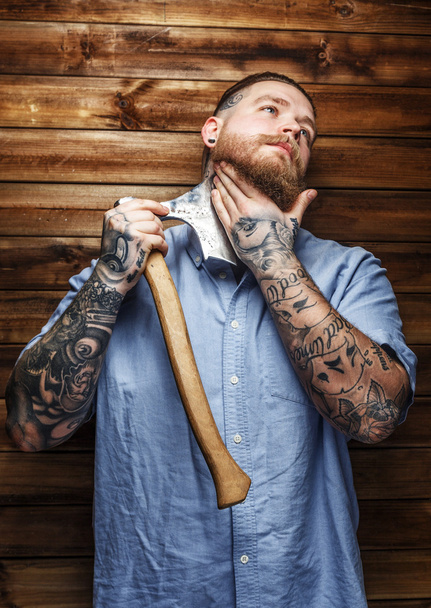 Огромный жестокий мужчина с татуировками бреет бороду
 - Фото, изображение