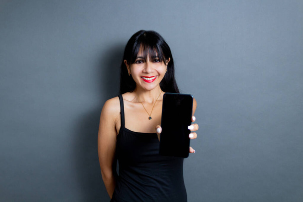 gelukkig latijn jonge vrouw tonen mobiele telefoon scherm - Foto, afbeelding