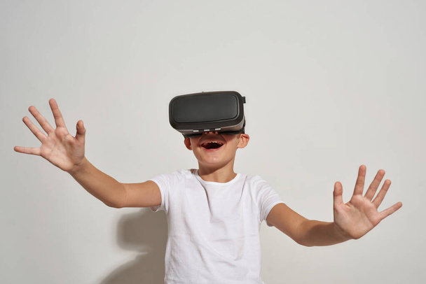 Little boy using virtual reality headset. Male child of zoomer generation. Youngster lifestyle. Virtual technology. Entertainment and leisure. Isolated on white background. Studio shoot. Copy space - Φωτογραφία, εικόνα