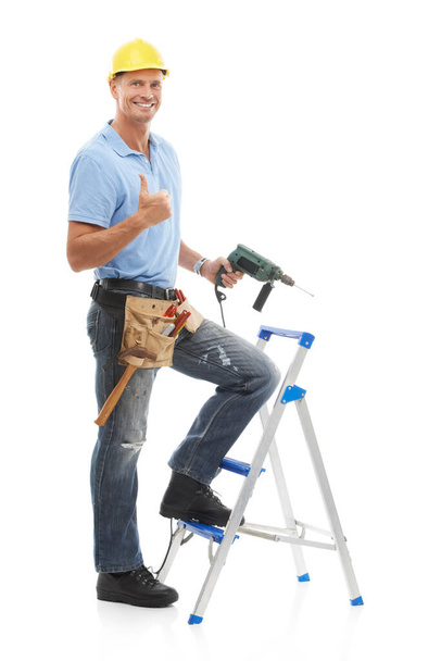 Thumbs up, portrait and repairman in a studio with a drill, tool belt and ladder for maintenance. Happy, smile and male industry worker or handyman with tools for repairs isolated by white background. - Photo, Image