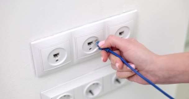 Hand connects internet cable to Wi-Fi extension cord that is in electrical outlet on wall concept - Materiaali, video