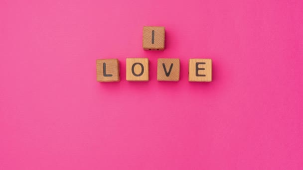 Drewniane kostki stop-motion ze zwrotem I Love You Baby Może na pustym kolorowym różowym tle. Słowa miłości są zrobione z liter z drewna na Walentynki i dla twojej dziewczyny, chłopaka - Materiał filmowy, wideo