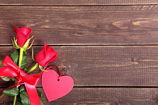 Fondo de San Valentín de etiqueta de regalo y rosas rojas en madera. Espacio fo
 - Foto, Imagen