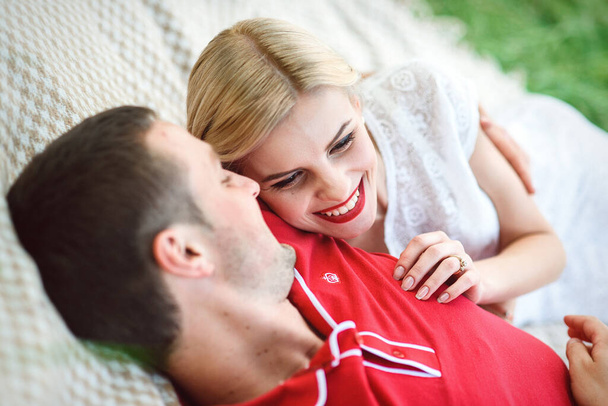 paar in liefde een blond meisje en een man in een rood t-shirt bij een picknick in een park met groen gras - Foto, afbeelding