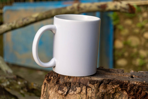 A close-up photo of a white mug in a peaceful park setting, showcasing the beauty and serenity of taking a break surrounded by nature - Fotó, kép