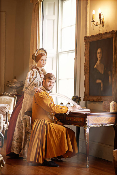 We have serious matters to attend to. an aristocratic couple writing a letter at an ornate table - Foto, Bild