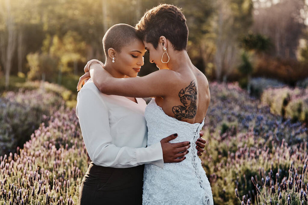 Married couple, lesbian and hug in embrace for LGBT, gay or transgender relationship in the nature outdoors. Happy women hugging for wedding, marriage or commitment in support for sexuality together. - Photo, Image