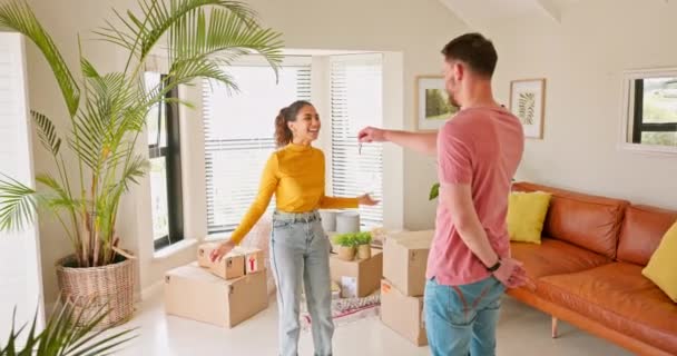 Moving, couple and man with keys for woman, hug and real estate success, happy and smile in their new house. Property, purchase and young homeowner sharing good news with girlfriend about home loan. - Záběry, video