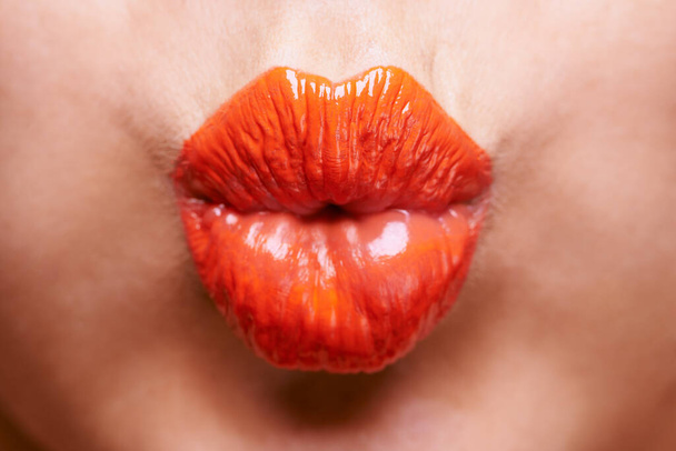 Pucker up. a womans pouting lips covered in shiny orange lipstick - Photo, Image