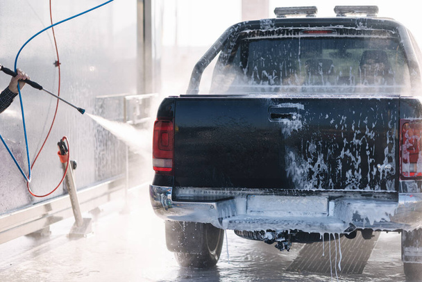 男性のプロセスは、セルフサービスの車の洗浄ステーションで自分の車を洗う. - 写真・画像