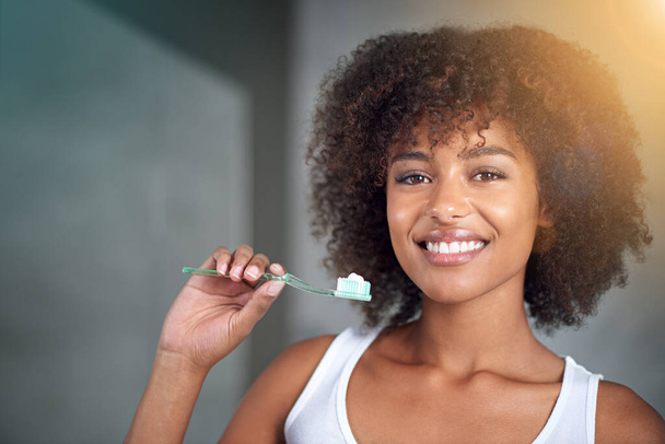 Taking care of my pearly whites. Cropped portrait of a young woman brushing her teeth in the bathroom - Foto, Imagen