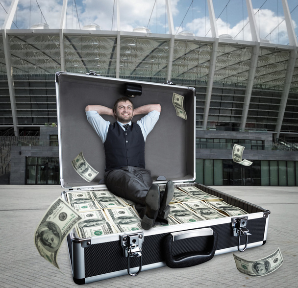 Feliz hombre de negocios se sienta en el caso lleno de dólares
 - Foto, imagen