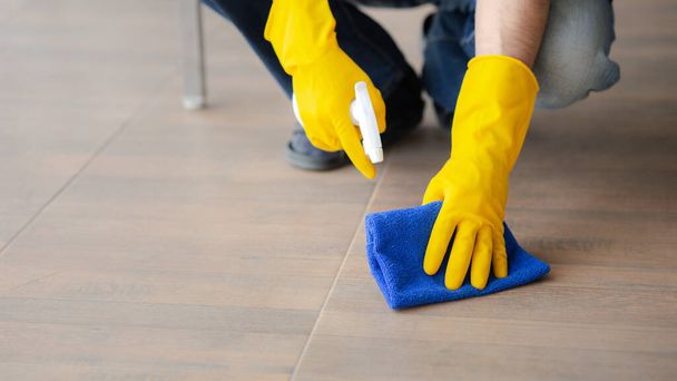 Osoba sprzątająca pokój, personel sprzątający używa tkaniny i środka dezynfekującego do wycierania podłogi w biurze firmy. Sprzątacze. Utrzymanie czystości w organizacji. - Zdjęcie, obraz
