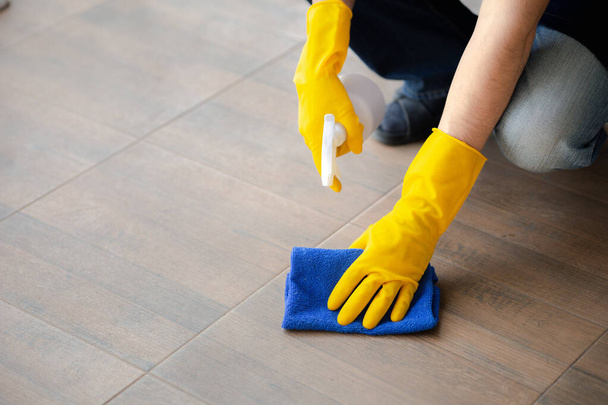Person cleaning the room, cleaning staff is using cloth and spraying disinfectant to wipe the floor in the company office room. Cleaning staff. Maintaining cleanliness in the organization. - Photo, image