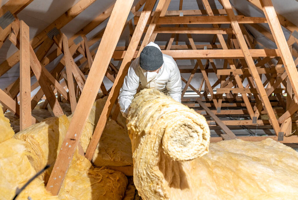 a man insulates the roof and ceiling of the house with glass wool - Fotografie, Obrázek
