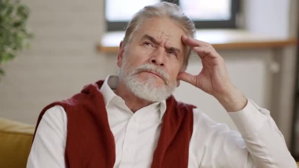 Крупним планом портрет пенсійного старшого бородатого чоловіка, який думає про своє життя, сидячи вдома сам, торкаючись його лоба і зітхаючи
 - Кадри, відео