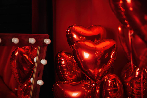Extravagant bedroom luxury interior with love glamour decoration at Valentine day in studio. Balloons by heart shaped and at illuminated mirror romantic cozy atmosphere at vivid red background. - Zdjęcie, obraz