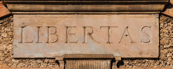 Libertas: ősi latin szó fro szabadság és szabadság, régi felirat tetején Lucca város falai  - Fotó, kép