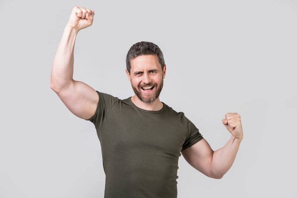 glad strong muscular man wear tshirt. strong muscular man isolated on grey background. strong muscular man in studio. photo of strong muscular man with stubble. - 写真・画像