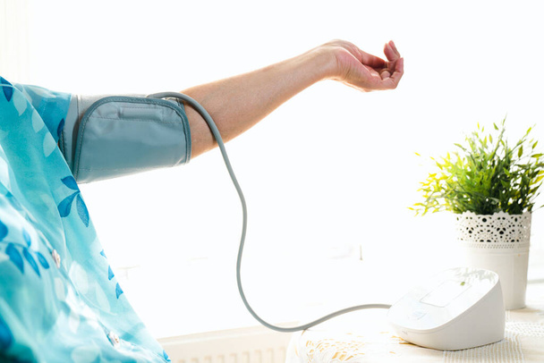 Mujer mayor examinando su presión arterial en su brazo - Foto, Imagen