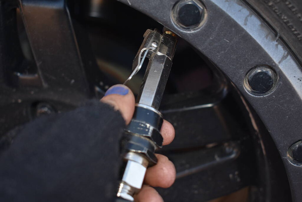 Female Hand Checking Air Pressure in Vehicle Tire. High quality photo - Zdjęcie, obraz