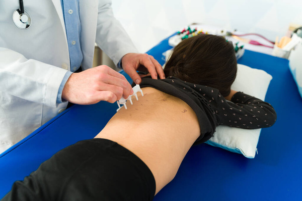 Közelkép egy spanyol fiatal gyerekről, aki bőrszúrásos tesztet vagy SPT-t csinál a hátán a gyermekorvos rendelőjében. - Fotó, kép
