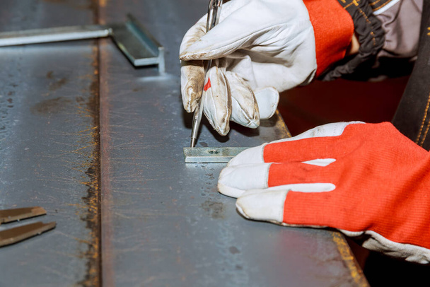 Marcas en una superficie metálica para perforar agujeros. El trabajador utiliza una herramienta para medir y marcar en una superficie de hierro. - Foto, imagen