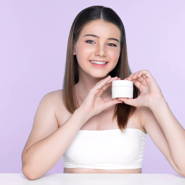 Young charming girl with natural beauty, perfect smooth skin hold lotion, cream, moisturizer jar. Beautiful girl show skincare product smiling on isolated background. - Zdjęcie, obraz
