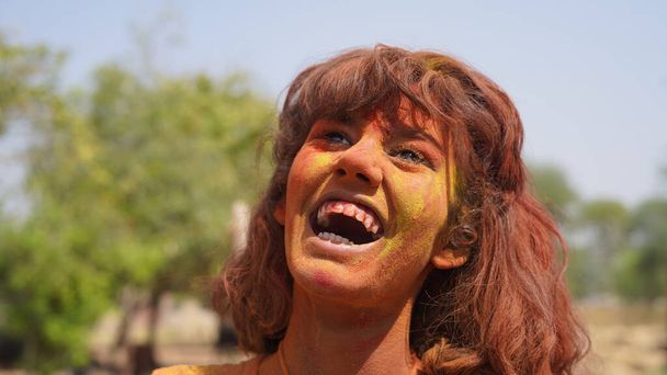 Menina bonita posando com explodindo rosa e amarelo pó Holi em torno dela - Foto, Imagem