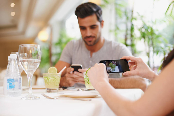 Capturing their times together. A woman taking a picture while dining out with her partner at a restaurant - Foto, Imagen