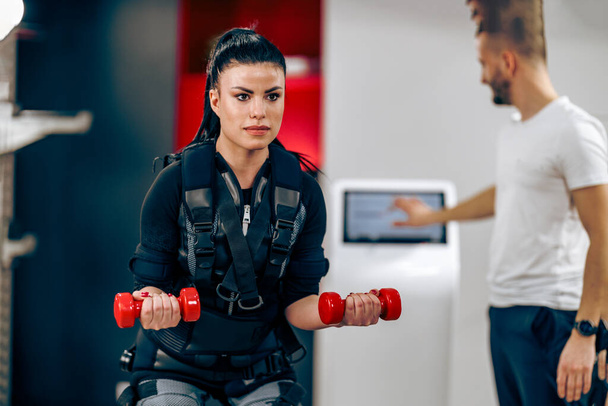 Young woman is doing EMS personal training with coach in the gym. - Foto, Bild