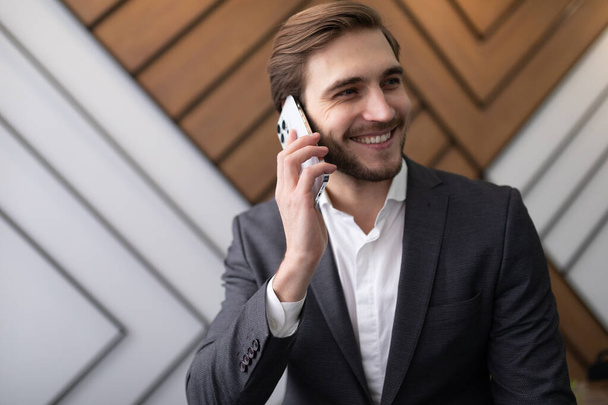 confident man businessman in a jacket speaks on the phone in the office. - Photo, Image
