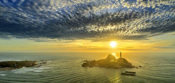 Landscape of small island with ancient lighthouse at sunrise sky is beautiful and peaceful. This is only ancient lighthouse is located on island in Vietnam - Photo, Image